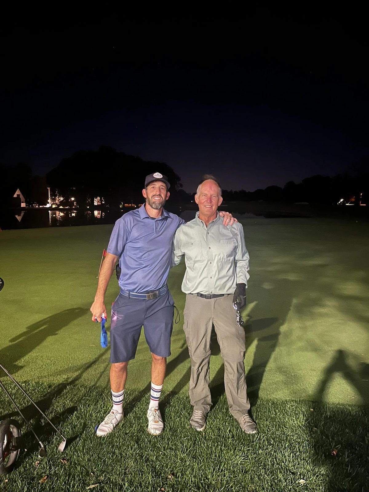 Two Fore The House golfers posing on a floodlit course at night