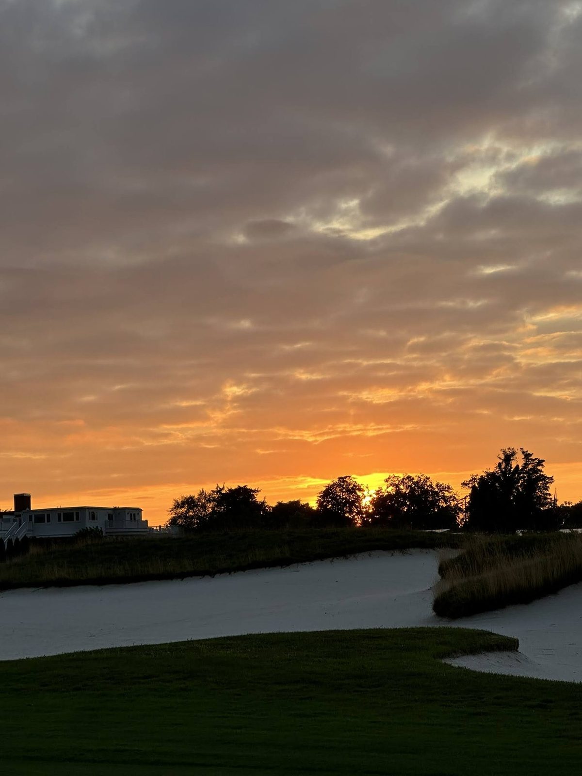 The sun going down behind a greenside bunker